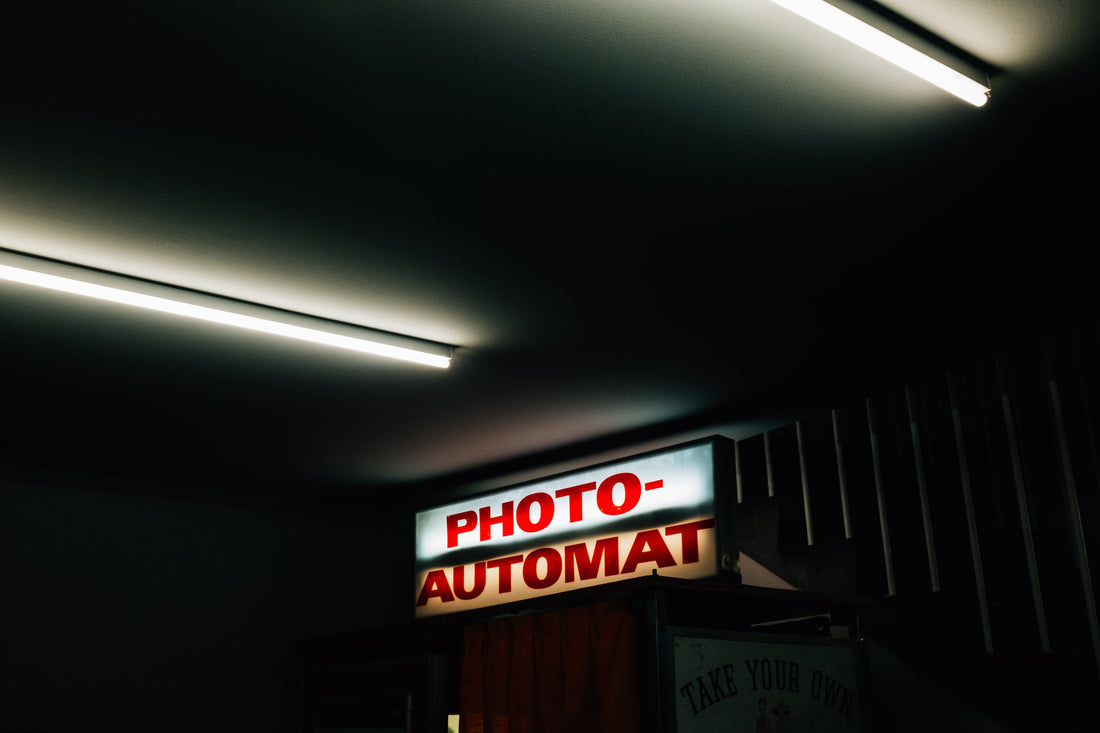 Retro “PHOTO-AUTOMAT” lightbox glowing in a dim room—capturing the nostalgic, creative energy behind Inkdnylon Custom Apparel’s custom embroidery, screen printing, and branded merch in Chicago.
