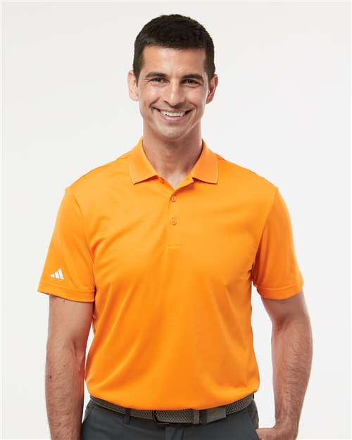 Man wearing an orange Adidas polo shirt on a white background