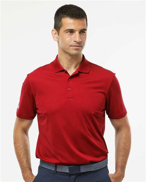 Man wearing a red short-sleeve polo shirt with a collar and button placket, dark trousers, and a gray belt.