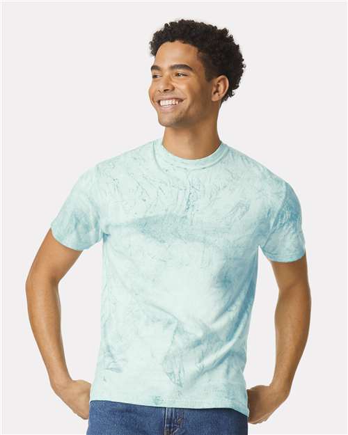 Smiling man wearing a light blue marbled short-sleeve t-shirt with hands on hips