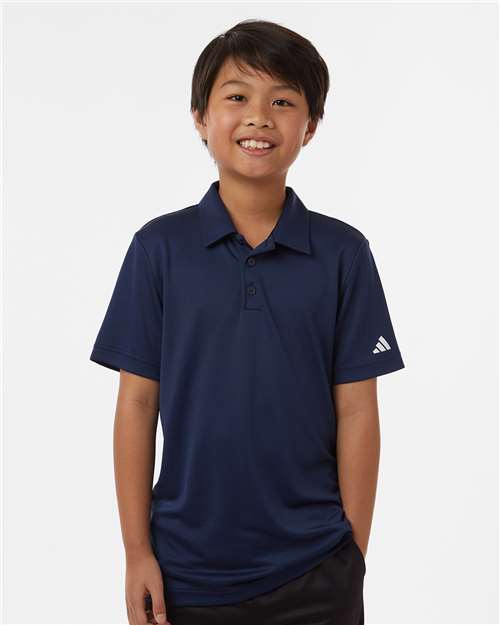 Child wearing a navy blue polo shirt with a white logo on a white background