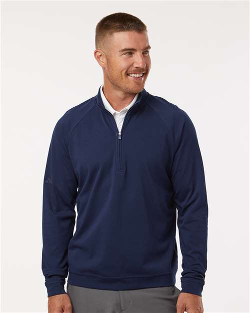 Man wearing a navy blue quarter-zip pullover with raglan sleeves over a white collared shirt.