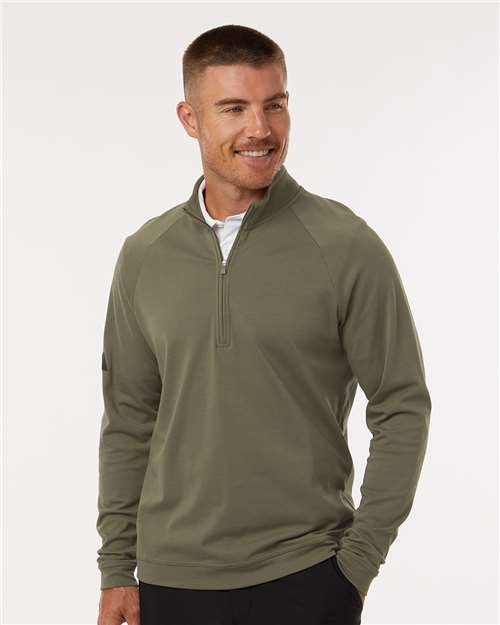 Man wearing an olive green quarter-zip pullover with raglan sleeves over a white shirt