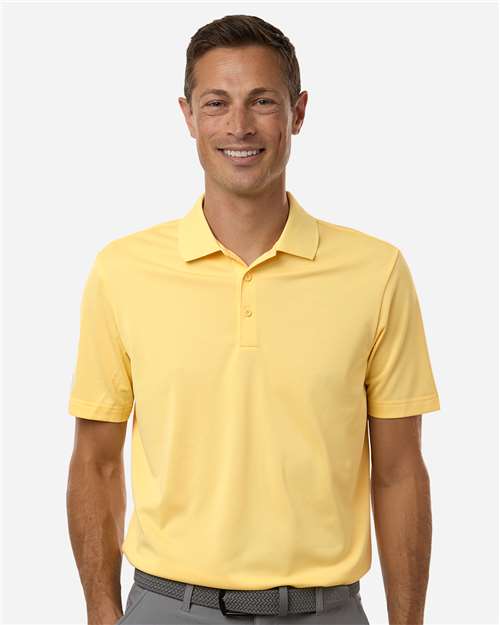 Man wearing a yellow short-sleeve polo shirt with a collar and button placket, gray pants, and a dark belt.