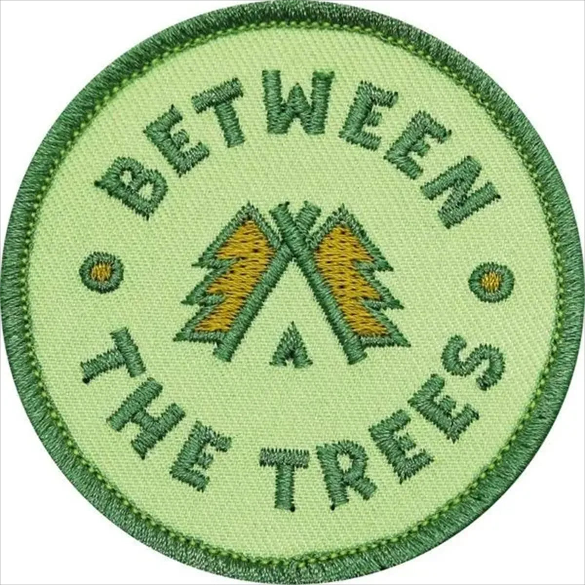 Circular patch with 'Between the Trees' text and tree design on a light green background