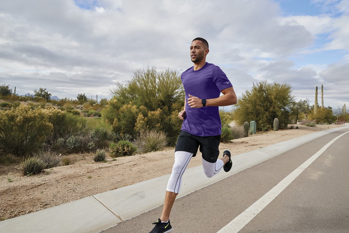 Man running on a road in a desert landscape